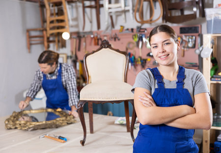 Female restorer demonstrating restored luxury chair in workshopの写真素材