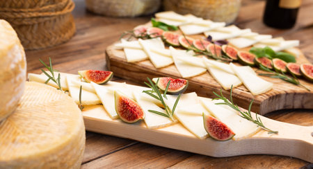 Delicious yummy cheese mix with figs on wooden board in restaurant. Tasting, degustation.の写真素材
