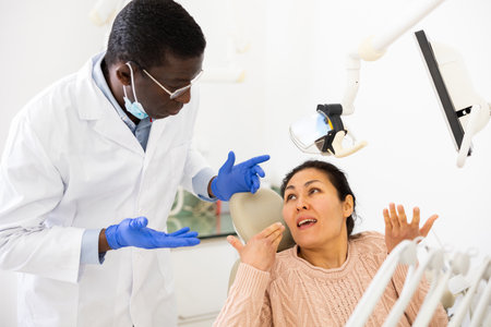 Asian woman with toothache sitting in chair at dentist appointmentの写真素材
