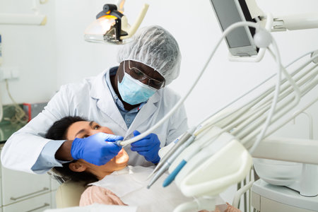 Focused dentist with female patient during teeth treatment in dental officeの写真素材