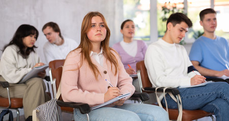 Girl student listening to lecture and taking notes in auditoriumの写真素材