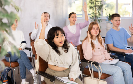 Young Asian female student raising hand to answer at lectureの写真素材