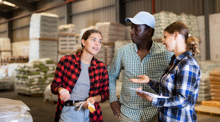 Workers and manager discussing completed work in large warehouseの写真素材