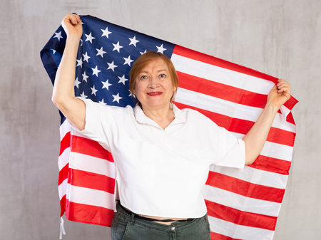 Cheerful senior woman standing confidently with american flagの写真素材
