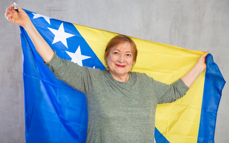 Cheerful senior woman standing confidently with bosnian flagの写真素材