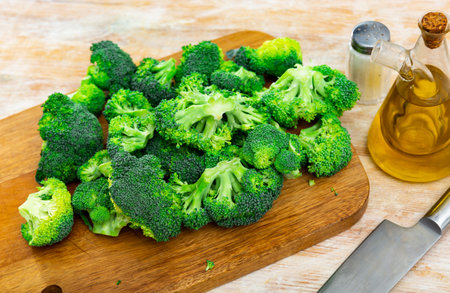 Green raw broccoli inflorescences on wooden cutting board with seasoningsの写真素材