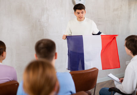 Young teacher holding flag of France in front of group of studentsの写真素材