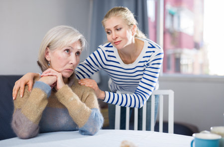 Adult daughter is trying to comfort her mature motherの写真素材