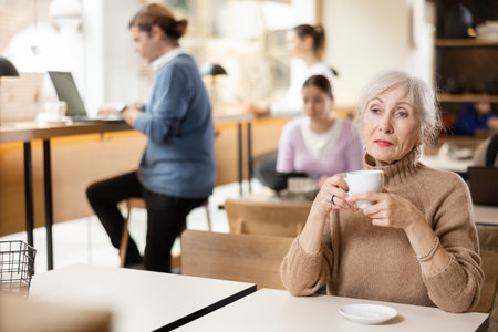 Calm mature woman enjoying peace and quiet alone in cozy cafeの写真素材