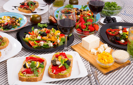 Many plates with tasty vegetarian food and wine in glassの写真素材