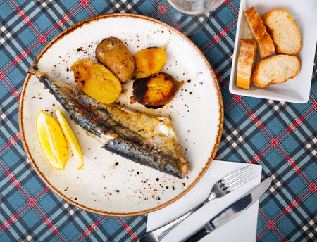 on plate, light and healthy lunch of whole fried mackerel with french fries and slice of lemonの写真素材