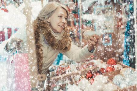Woman is preparing for Christmas and choosing balls on the treeの写真素材