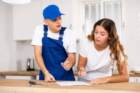 Positive plumber tells an young housewife where to sign an invoice for work performed.の写真素材