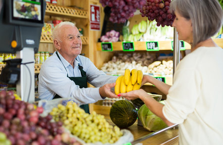 Old man cashier serving customer in greengrocerの写真素材
