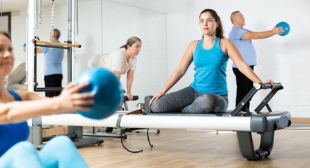 Young girl performing pilates exercises on reformer in fitness studioの写真素材