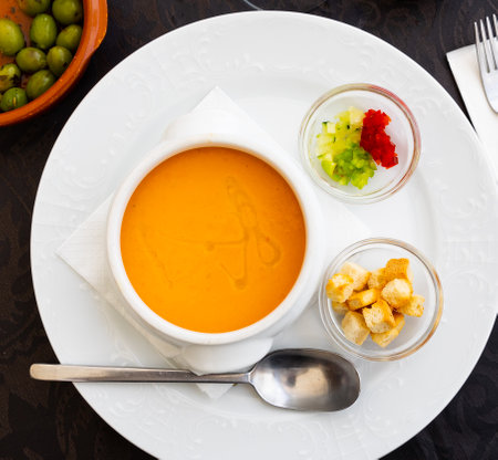 Cold soup gazpacho in bowl served with vegetables, baked breadsの写真素材