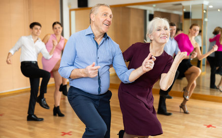 Happy older couple performing a paired ballroom dance in ballroom