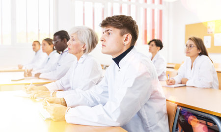 Young man in white coat attending lecture in medical universityの写真素材