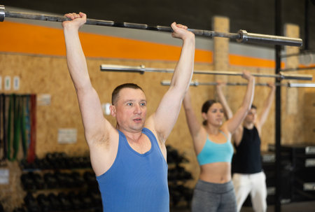 Concentrated athletic man performing exercises with barbell in gymの写真素材