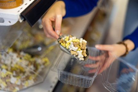 Female hands filling container with dry food for dogs in pet storeの写真素材