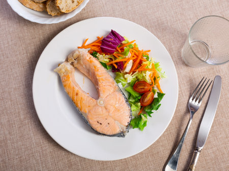 Lunch at Mediterranean restaurant.slice of fried salmon with salad of fresh vegetables.の写真素材