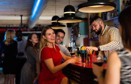 Man bartender making alcohol cocktail for couple in nightclubの写真素材