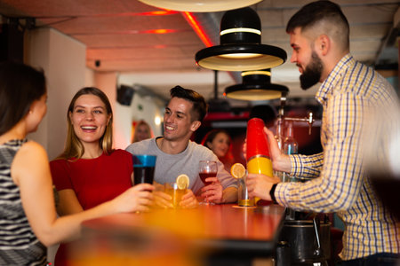 Happy people and bartender shaking cocktail mixerの写真素材