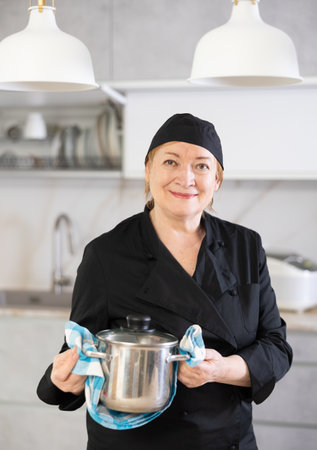 Portrait of a smiling mature female chef with a saucepan in her handsの写真素材
