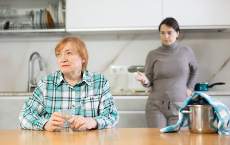 Distressed mature woman in argument with her daughter in kitchenの写真素材