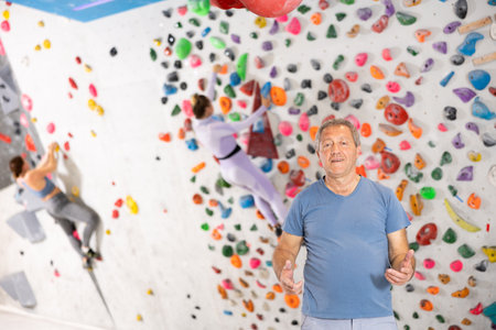 Portrait of positive elderly male coach against background of climbing wallの写真素材