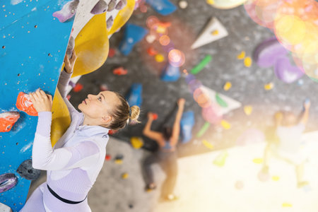 Adult woman practicing rock climbing on climbing wallの写真素材