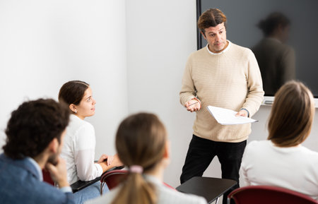 Confident male leader, trainer near interactive board talking to group of people, brainstorming, discussing ideas in auditoryの写真素材