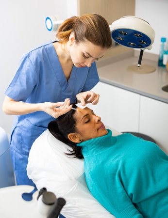 Woman patient receiving forehead injection at clinicの写真素材