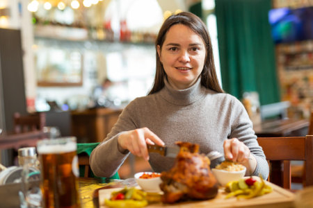 Positive brunette having lunch in cafe with roasted ham hock and beerの写真素材