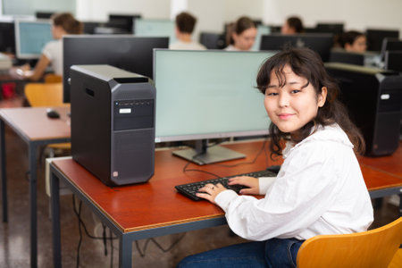 Smart Asian female teenager learning computer science while she is using a PC in the computer classroomの写真素材