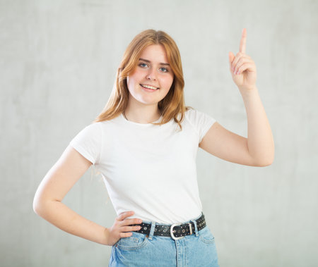 Girl point finger at arm with copy space for promotion over studio wallの写真素材