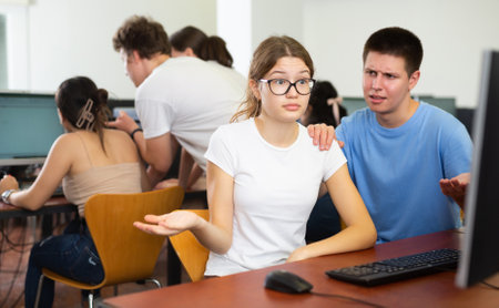 Helpless teenager boy and girl studying in computer classの写真素材