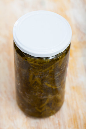Canned green spinach in glass jar on wooden surfaceの写真素材