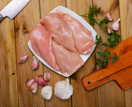 Raw chicken breast fillet with garlic and greensの写真素材
