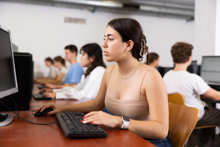 Side view on diligent college girl studying using pc in computer classの写真素材