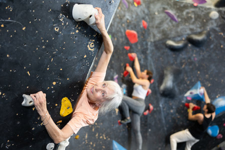 elderly active female pensioner reached top of bouldering wallの写真素材