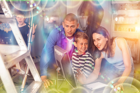 Happy family using computer in closed escape room stylized as bunkerの写真素材