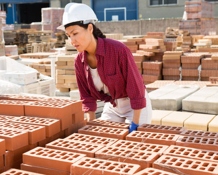 Asian construction shop worker stacks bricks on an open-air site