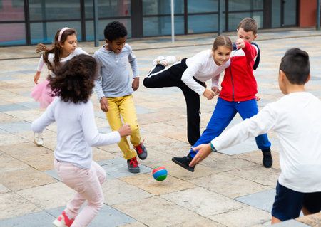 Group of active schoolchildren playing football at summer dayの写真素材