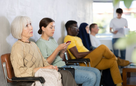 Elderly woman sitting on chair waiting in line at reception