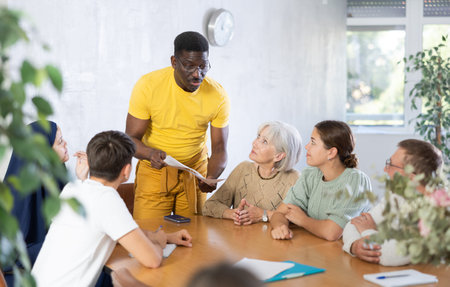 Experienced male coach conducts training for people of different nationalities in classroom