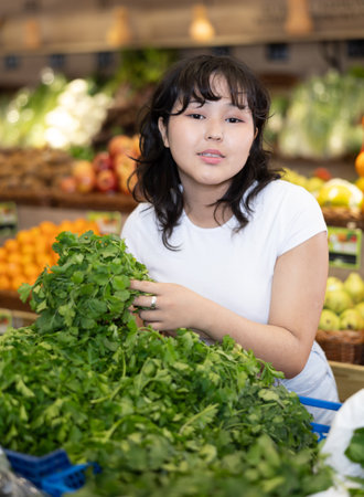 Young asian girl hoosing fresh greens in farm storeの写真素材