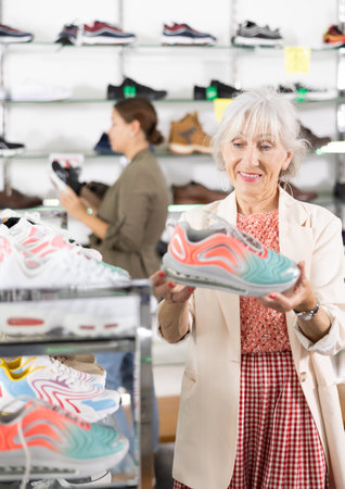 Elderly woman choosing training shoes in shoe storeの写真素材