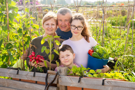 Portrait of friendly family with children at the fence of gardenの写真素材