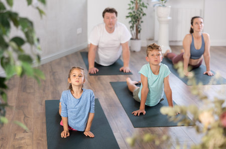 Preteen children practice yoga and Pilates with parents